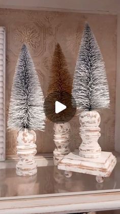 three small christmas trees sitting on top of a table in front of a window with shutters