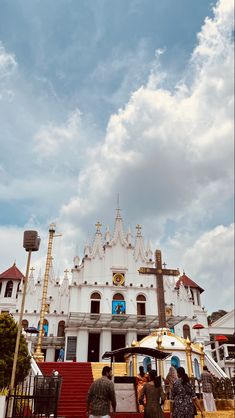 people are standing in front of a large white building with a cross on the top