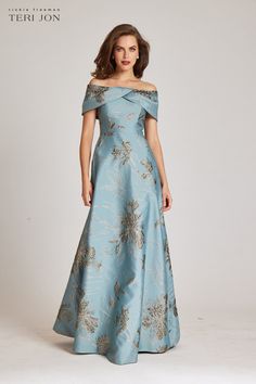 A jaw dropping evening gown! This Jacquard metallic gown has an off the shoulder twisted neckline. The cap sleeves add an elegant touch while also offering the ideal amount of sleeve coverage that is always sought out. Also incorporated is a visible high waistline and full a-line skirt to elevate the look. This is a mo Sleeved Mother Of The Bride Dresses, Dusty Blue Mother Of The Bride Dress Long, Mother Of The Groom Dresses Formal, Elegant Mother Of The Bride Dresses Blue, Mom Dress For Wedding Mothers Gowns, Mom Of The Bride Dresses Modern, Classy Dress Outfits For Wedding, Sister Of The Bride Dress, Mother Of The Bride Dresses Vintage