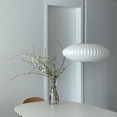 a vase with flowers sitting on top of a white table next to a chair and mirror