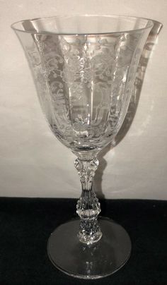 a clear glass vase sitting on top of a black tablecloth covered floor next to a white wall