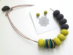 a necklace made out of felt and beads on a white surface with a card next to it