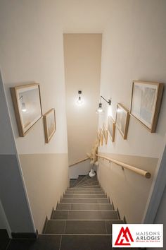 the stairs are lined with framed pictures on the wall and in between them is a lamp