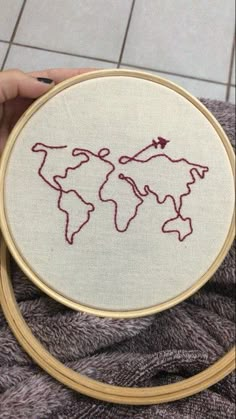 someone is holding up a cross stitch world map