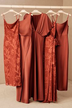 three dresses hanging on a rack in front of a wall