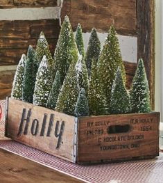 christmas trees are in a wooden crate on a table