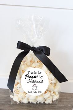 a bag filled with white popcorn sitting on top of a wooden table next to a black ribbon