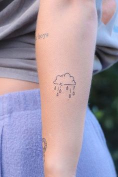 a woman's arm with a tattoo on it that has a cloud and rain drawn on it