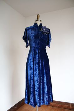 "Drool worthy icy blue velvet dream dress from the 1930s. This one features elegant lines, a high neckline, uniquely draped sleeves that feature weighted inserts so they hang perfectly, and a big flower on the front. Snaps on the side for closure.  Label: none Measurements: { xsmall } Bust: 33\"  Waist: about 26\"  Hips: 35\" Length: 47\" Condition: nearly excellent vintage condition with minor signs of wear - in some lighting I noticed a few faint spots that aren't noticeable overall as well as the flower doesn't sit perfectly. I had to temporarily pin it into place so may need some extra pins to have it sit nicely (yes I tried steaming it) - sold as found.  ☆Shop☆ http://www.trunkofdresses.com/" Blue Fitted Velvet Dress, Dark Blue Velvet Dress, Clue Costume, 40s Outfits, Oc Clothes, Draped Sleeves, Blue Velvet Dress, Artsy Photos, 1930s Dress