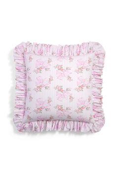 a pink pillow with ruffled edges and flowers on the front, sitting on a white surface