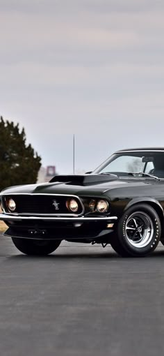 an old black muscle car parked in a parking lot