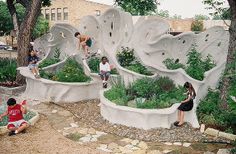 children are playing in an outdoor garden with rock formations and plants on the ground, while adults watch