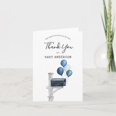 a thank you card with blue balloons and a mailbox on the table next to it