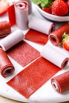 rolled up strawberries sitting on top of a table next to rolls of wax paper