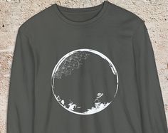 Elevate your wardrobe with our Man on the Moon long-sleeve shirt, crafted for those who appreciate both style and comfort. Made with 100% ring-spun cotton, this personalized shirt offers a soft, cozy feel and a timeless design that's perfect for any casual occasion. Features: 100% Ring-Spun Cotton: Enjoy unmatched softness and durability. Medium Fabric: Weighing 6.1 oz/yd² (206.8 g/m this shirt provides a comfortable, substantial feel. Classic Fit: Designed with a relaxed fit for effortless styl Black Long Sleeve Top With Moon Print, Long Sleeve Cotton Shirt With Graphic Design, Cotton Long Sleeve Shirt With Graphic Design, Long Sleeve Cotton Tops With Moon Print, Cotton Long Sleeve Tops With Moon Print, Long Sleeve Cotton Top With Moon Print, Cotton Tops With Moon Print For Fall, Fall Cotton Top With Moon Print, Cotton Top With Moon Print For Fall