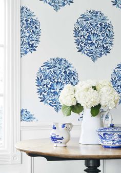 blue and white floral arrangement in front of wallpaper with vases on wooden table