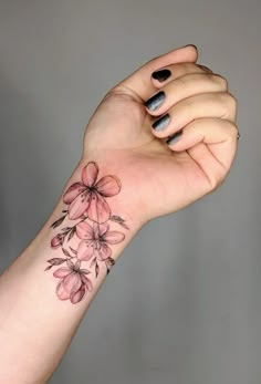 a woman's arm with pink flowers on it and black dots around the wrist