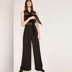 Contrast Fabric Palazzo Jumpsuit. Sheer Top With Shiny Details And Pockets. Bow At The Neck And Sleeveless. Front Button Fastening. Palazzo Trousers With Front Zip And Press Stud Fastening. Upper: 98% Viscose, 2% Metallized Fiber Lower: 100% Polyester Black Bodysuit For Workwear In Spring, Spring Workwear Black Bodysuit, Black Bodysuit For Spring Workwear, Black Bodysuit For Work In Spring, Chic Black Summer Pantsuit, Summer Evening High-waisted Pantsuit, Elegant High-waisted Jumpsuits And Rompers For Summer, Black Bodysuit For Workwear In Summer, Black Bodysuit For Summer Workwear