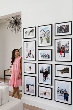 a woman standing next to a wall with pictures on it