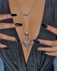 a woman with black fingernails and tattoos on her chest