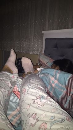 two people laying in bed with their feet up