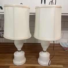 two white lamps sitting on top of a wooden table