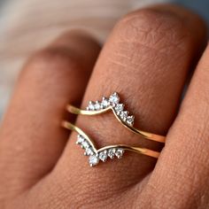 a person's hand with two gold rings on their fingers and one is wearing a diamond ring