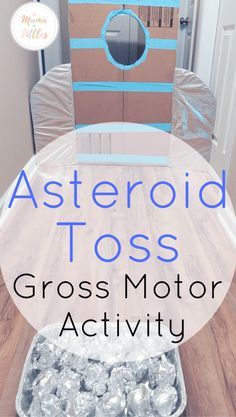 a cardboard box sitting on top of a wooden floor with foil wrapped around it and the words, asteroid toss gross motor activity