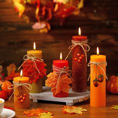 candles with fall leaves and pumpkins around them