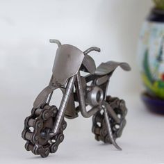 a toy bike made out of metal parts sitting next to a potted plant on a table