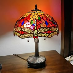 a lamp that is sitting on top of a wooden table in front of a red wall