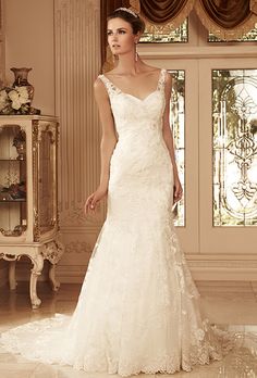 a woman in a wedding dress standing next to a window