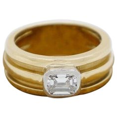 This lovely Tiffany & Co. vintage diamond ring from 1995, is crafted in vibrant 18k yellow gold. This classic piece features a beautiful emerald cut diamond at the center of a wide, ridged band, set horizontally along the ring, resting within a raised bezel setting crafted in platinum. The wide band has deep grooves which carry along the surface, graduating slightly towards the back, providing a dramatic textured appeal. Stamped inside the shank is the official "Tiffany & Co" signature hallmark, Tiffany Atlas Rings, Vintage Diamond Ring, Tiffany Diamond, Wide Band Ring, Emerald Diamond Ring, Vintage Diamond Rings, Emerald Cut Diamond, Diamond Cocktail Rings, Platinum Engagement Rings