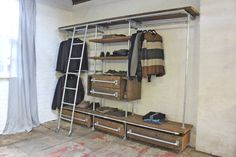 an industrial style clothing rack with drawers and ladders in a room that is being used as a storage unit