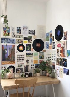 a table with some records on it and plants in pots next to the wall full of pictures