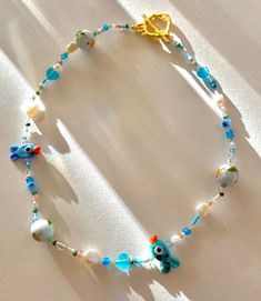 Gorgeous beaded necklace featuring two genuine murano glass fish beads, handpainted ceramic beads, Jade 2mm beads and selenite hearts, as well as genuine freshwater pearls and a 18k gold plated toggle clasp all strung on the best quality and very strong beading thread. Selenite is known to promote mental wellbeing and positivity as well as being calming and nurturing. Jade is a protective stone and can promote friendship-making this piece perfect for a loved ones birthday.  This item is absolute Ceramic Fish Necklace, Murano Glass Beaded Necklace For Gift, Unique Murano Glass Beaded Necklace For Gift, Handmade Adjustable Murano Glass Jewelry, Glass Heart Beads Jewelry, Glass Necklaces With Tiny Beads For Gifts, Glass Necklace With Tiny Beads For Gift, Murano Glass Beaded Necklaces With Colorful Beads For Gift, Handmade Murano Glass Beaded Necklaces With Round Beads