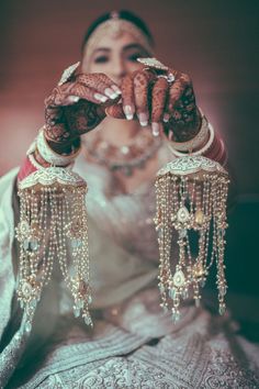 the bride is holding her hands up to show off her wedding jewelry