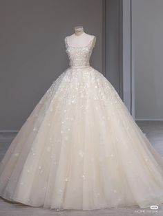 a white wedding dress on display in front of a gray wall and grey flooring