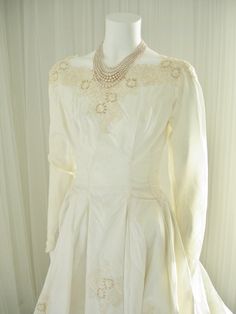 a white dress with pearls on the neck and sleeves