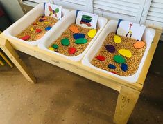 three trays filled with sand and paper cutouts on top of a wooden table