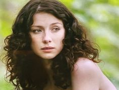 a woman with long curly hair is posing for the camera