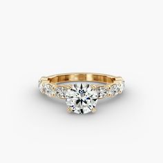 a yellow gold engagement ring with three stones on the band and a round center stone