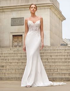 a woman standing in front of some steps wearing a wedding dress with an open back