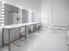 a white room with mirrors and lights on the wall, all lit up by stools