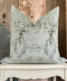 a blue pillow sitting on top of a white chair next to a wooden wall with peeling paint