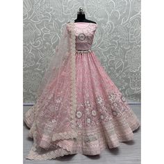 a pink lehenga on display in front of a wall