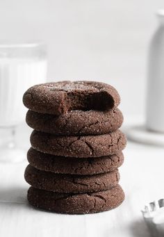 a stack of chocolate cookies next to a glass of milk