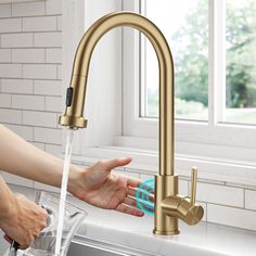 a person washing their hands under a kitchen faucet