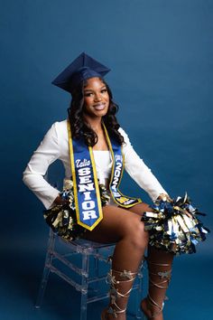 a woman sitting on top of a chair wearing a graduation sash