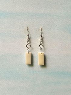 two square shaped earrings hanging from silver hooks